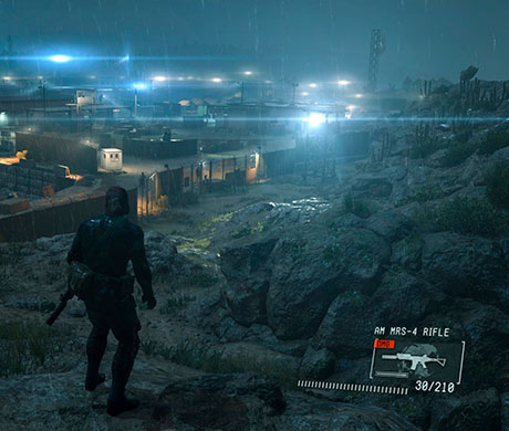 Imagen de Big Boss observando un campamento enemigo desde lejos en el juego Metal Gear V: Ground Zeroes.